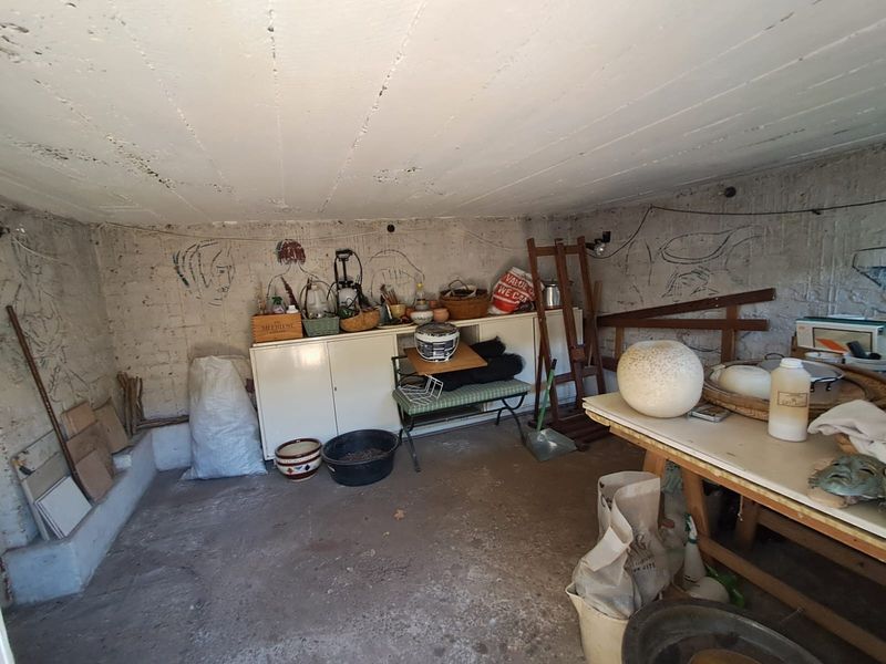 A utility or storage space featuring built-in cabinetry, concrete flooring, and an exposed concrete ceiling, currently used for storage.
