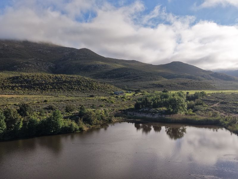 An aerial view of the farm property featuring a large dam set against a scenic mountain landscape.