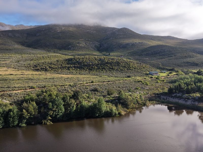 An aerial view of the farm property featuring a large dam and expansive mountain landscape.