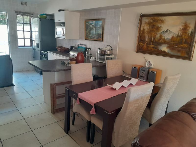 Open plan kitchen and dining area featuring tiled flooring, a breakfast bar, and functional cabinetry, offering a practical layout for daily living.