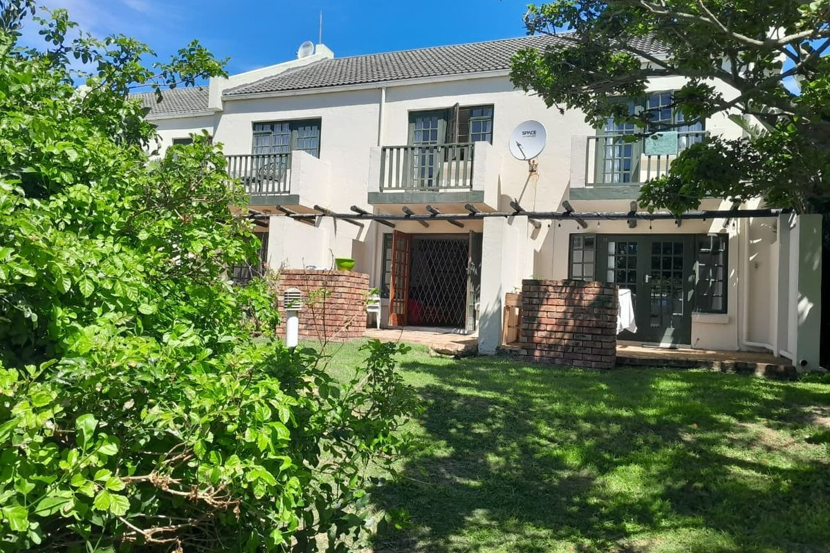 Rear view of the property featuring a private garden, brick-walled patio area, timber pergola, and upper-level balconies with french doors.