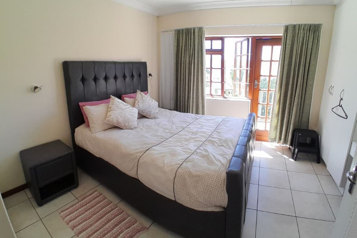 A bedroom featuring tiled flooring, built-in wardrobe storage, and a french door providing access to the exterior.