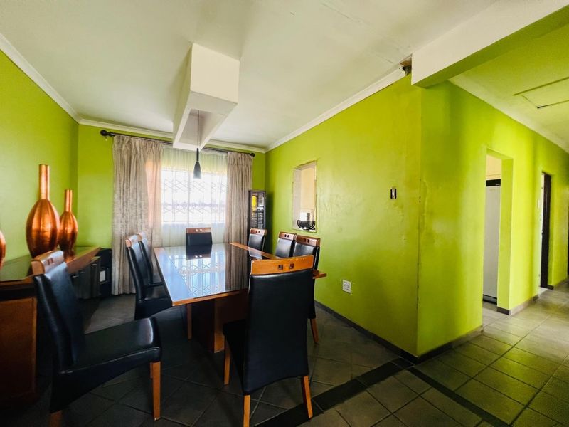Dining room featuring tiled flooring, a built-in bulkhead lighting feature, and security bars on the window, requiring cosmetic updates to the wall finishes.