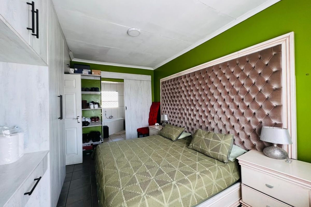 A bedroom featuring built-in cupboards, tiled flooring, and an en-suite bathroom access point. The room requires minor ceiling repairs and cosmetic updates.