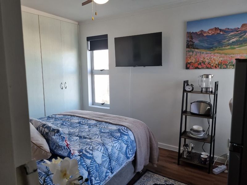 A well-maintained bedroom featuring built-in cupboards, laminate flooring, and a ceiling fan, providing a comfortable and functional sleeping space.