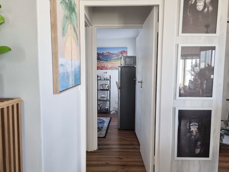 A view through a doorway into an adjacent room, featuring laminate flooring and neutral wall finishes.