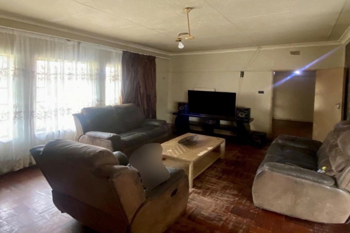 A living room featuring original parquet flooring and coved ceilings, currently requiring cosmetic updates and wall repairs to restore its appeal.