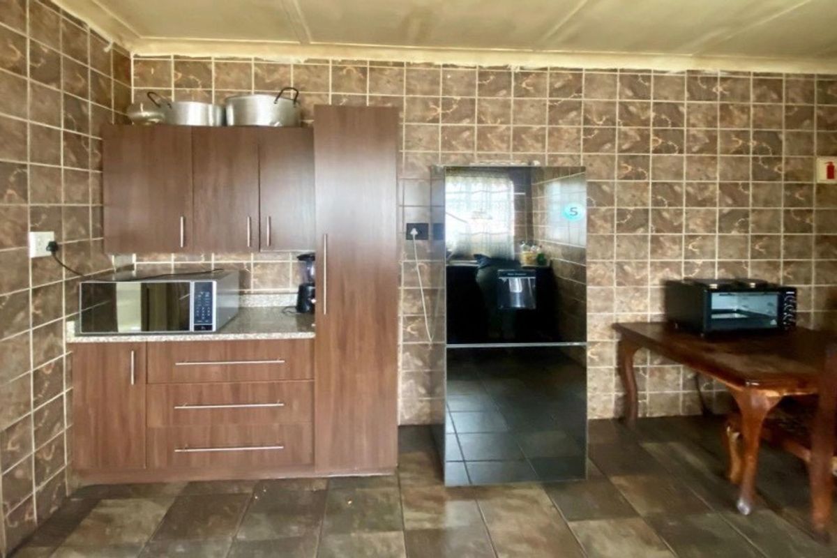 A dated kitchen featuring brown cabinetry, extensive wall tiling, and tiled flooring, offering potential for a modern renovation to update the space.