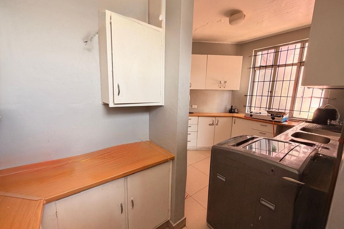 A functional kitchen featuring built-in cabinetry, laminate countertops, and a double bowl sink, with security bars installed on the window.