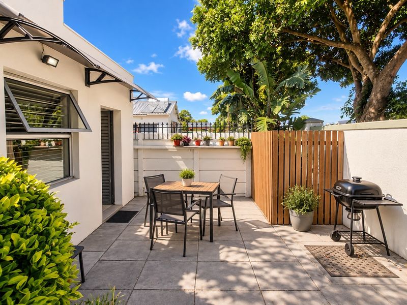A well-maintained paved patio area featuring a timber privacy screen, boundary wall, and outdoor lighting, perfect for relaxed outdoor dining and entertaining.