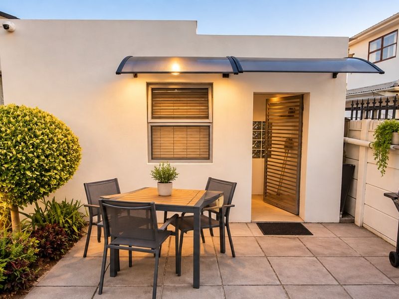 A well-maintained paved patio area featuring a modern awning, external lighting, and secure access, perfect for outdoor dining and relaxation.