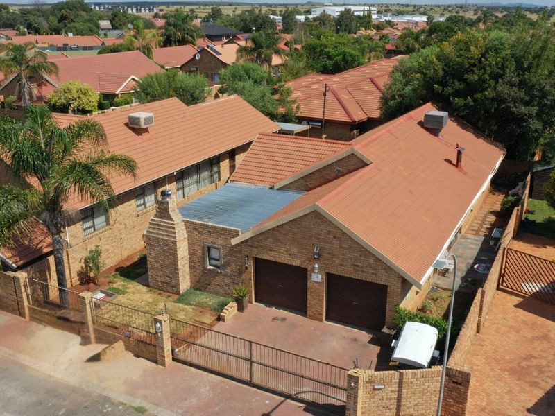 Aerial view of a facebrick residential property featuring a tiled roof, double garage, and secure perimeter walling in a suburban neighborhood.