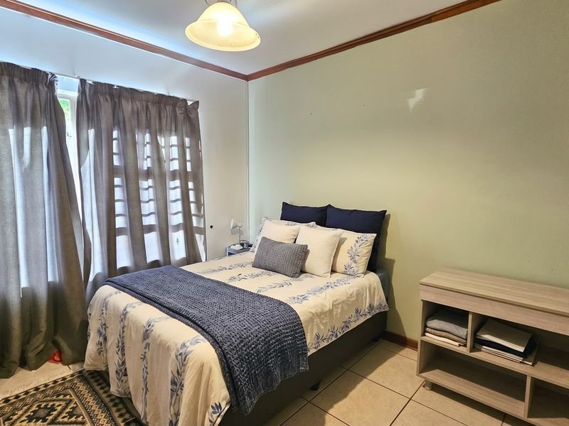 A functional bedroom featuring tiled flooring, neutral wall tones, and timber crown molding, offering a comfortable and well-lit living space.