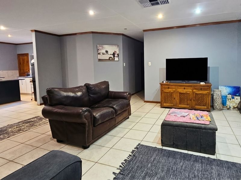 Spacious open-plan living area featuring tiled flooring, recessed lighting, and a prominent freestanding fireplace, seamlessly flowing into the adjacent kitchen space.