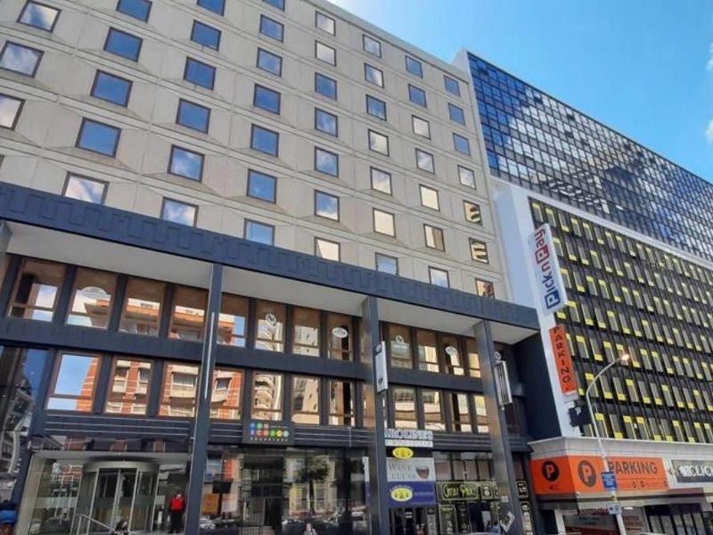 A multi-story commercial office building featuring a modern facade with large windows, ground-level retail signage, and integrated parking access.