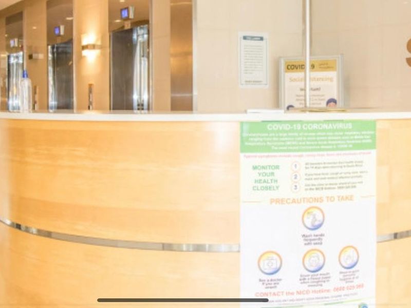 A professional office building lobby featuring a curved reception desk, elevator access, and modern security turnstiles.