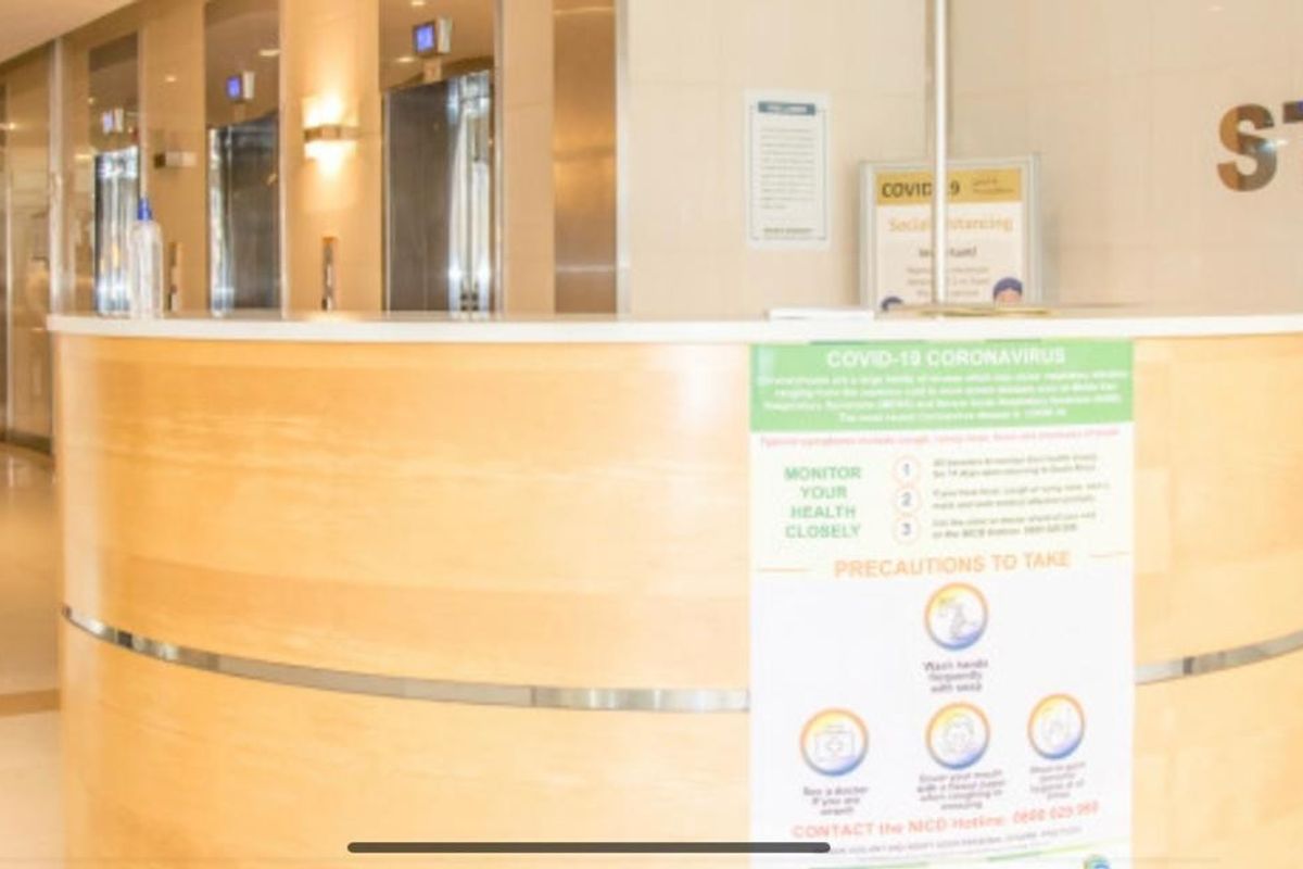 A professional office building lobby featuring a curved reception desk, elevator access, and modern security turnstiles.