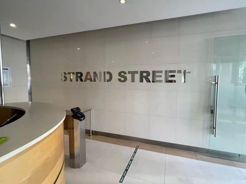 Modern office building entrance lobby featuring a reception desk, secure access turnstile, and professional tiled finishes.