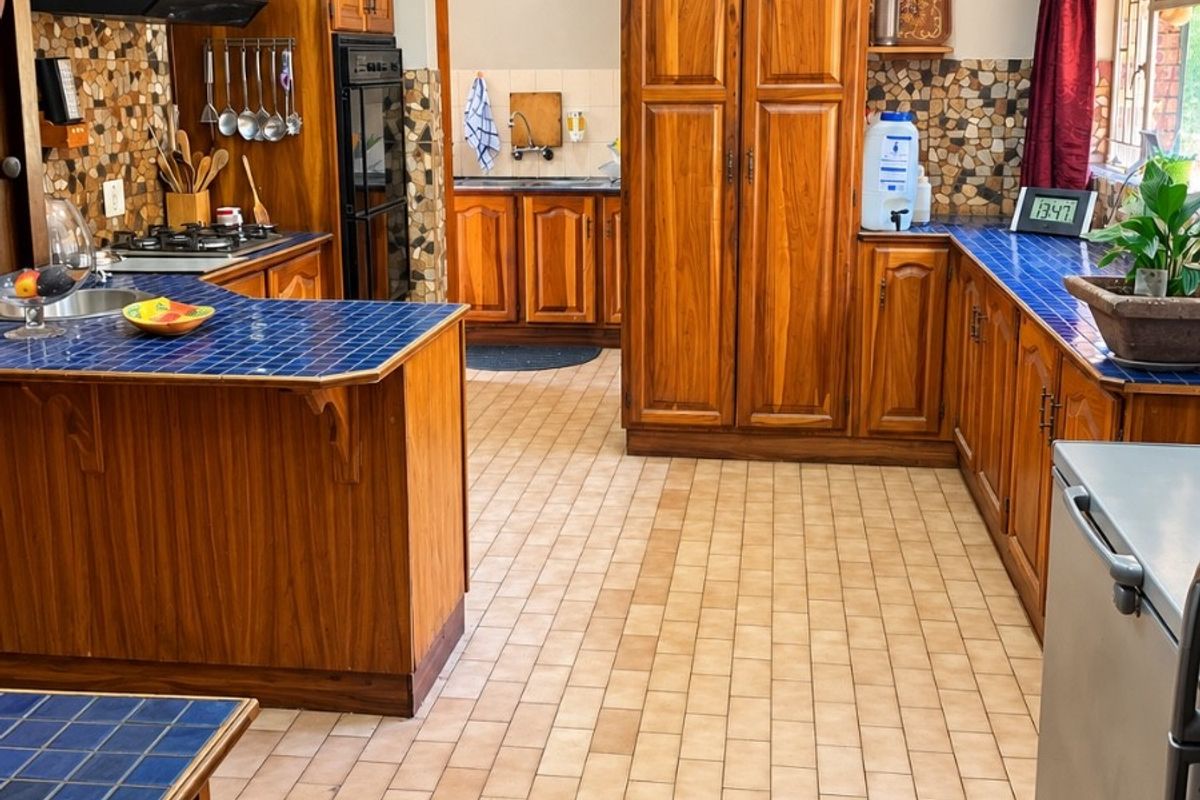 Spacious kitchen featuring traditional wooden cabinetry, blue tiled countertops, mosaic backsplash, and a functional layout with a separate scullery area.