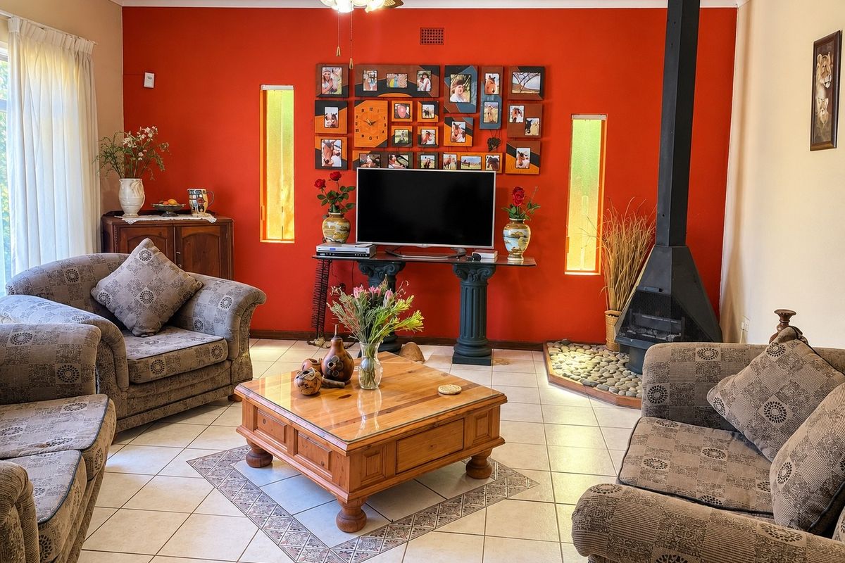 A living room featuring tiled flooring, a prominent red accent wall, a freestanding fireplace, and vertical windows providing natural light.