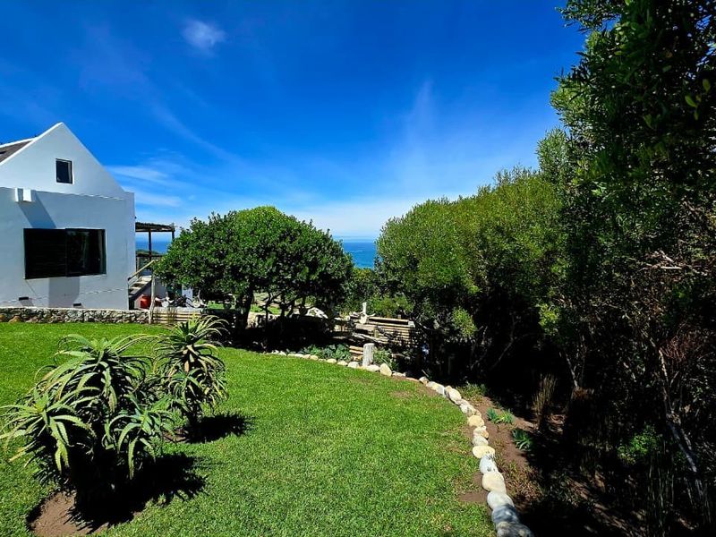 A well-maintained rear garden featuring stone edging, lush lawn, and a view of the white exterior facade of the house.