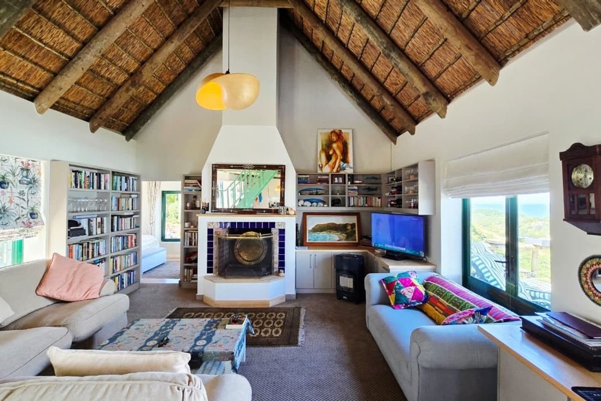 Spacious living room featuring a high vaulted thatched ceiling with exposed timber rafters and a central built-in fireplace with integrated shelving.