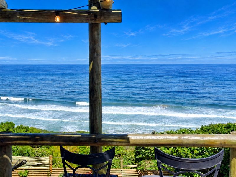 An elevated outdoor patio featuring a timber pergola and railing, offering expansive, unobstructed views of the ocean.
