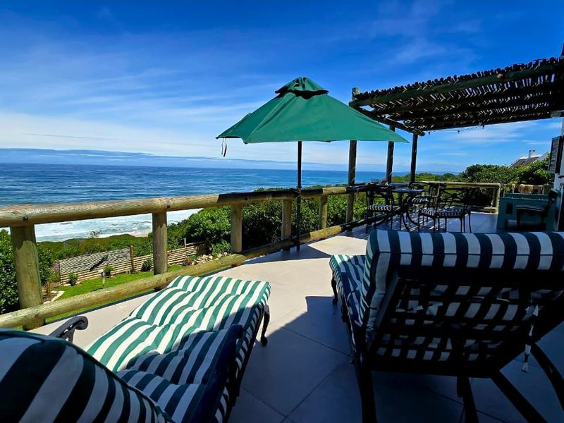 A spacious outdoor patio featuring a timber railing and pergola, offering expansive, unobstructed views of the ocean and coastline.