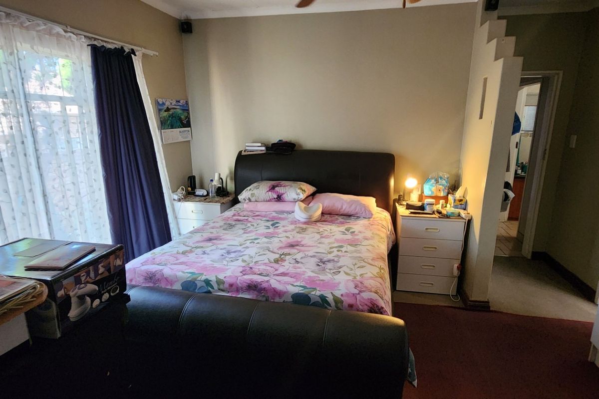 A bedroom featuring a sliding door for natural light, a ceiling fan, and a partial partition wall leading to an adjacent space.
