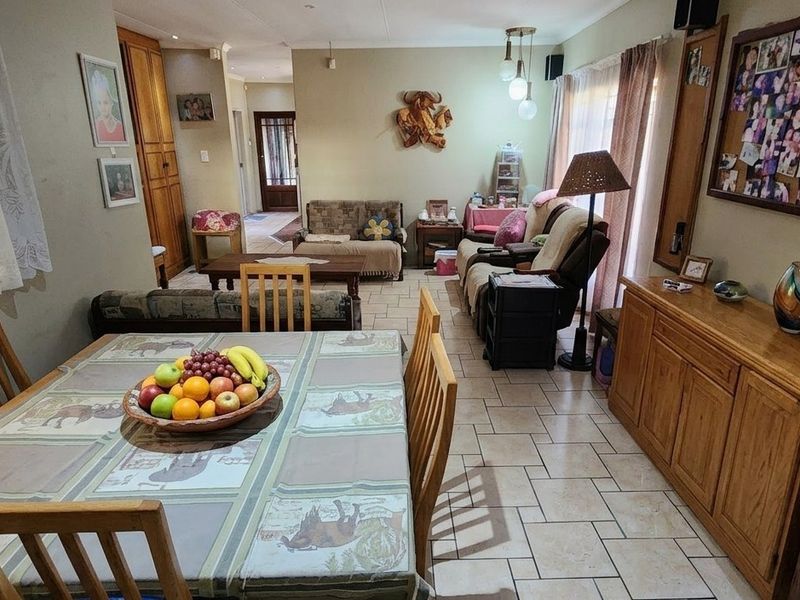 An open-plan living and dining area featuring tiled flooring and neutral wall tones, offering a functional layout for family living and entertaining.
