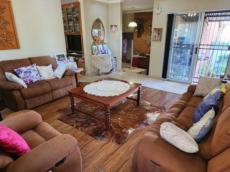 Spacious living room featuring laminate flooring, coving, and a sliding glass door providing access to the outdoor area.