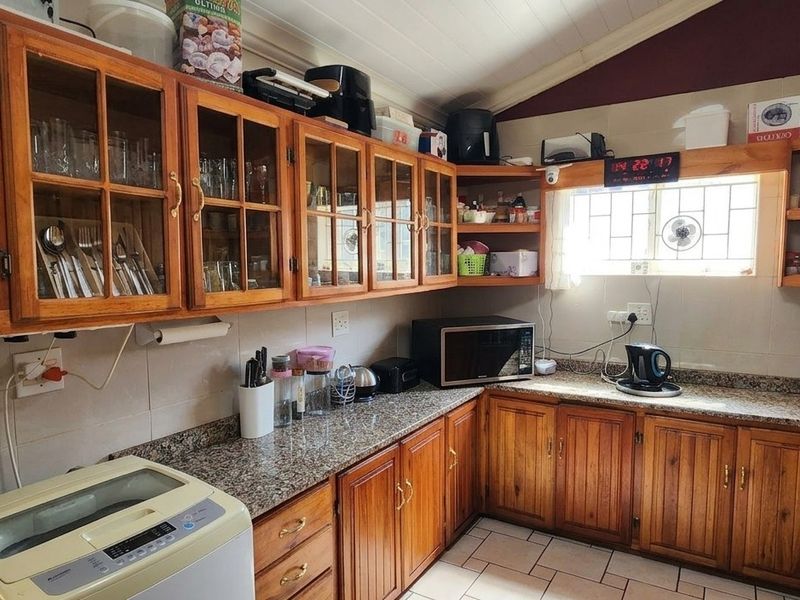 A functional kitchen featuring warm wooden cabinetry, granite countertops, and tiled flooring, offering a classic aesthetic with practical storage and workspace.