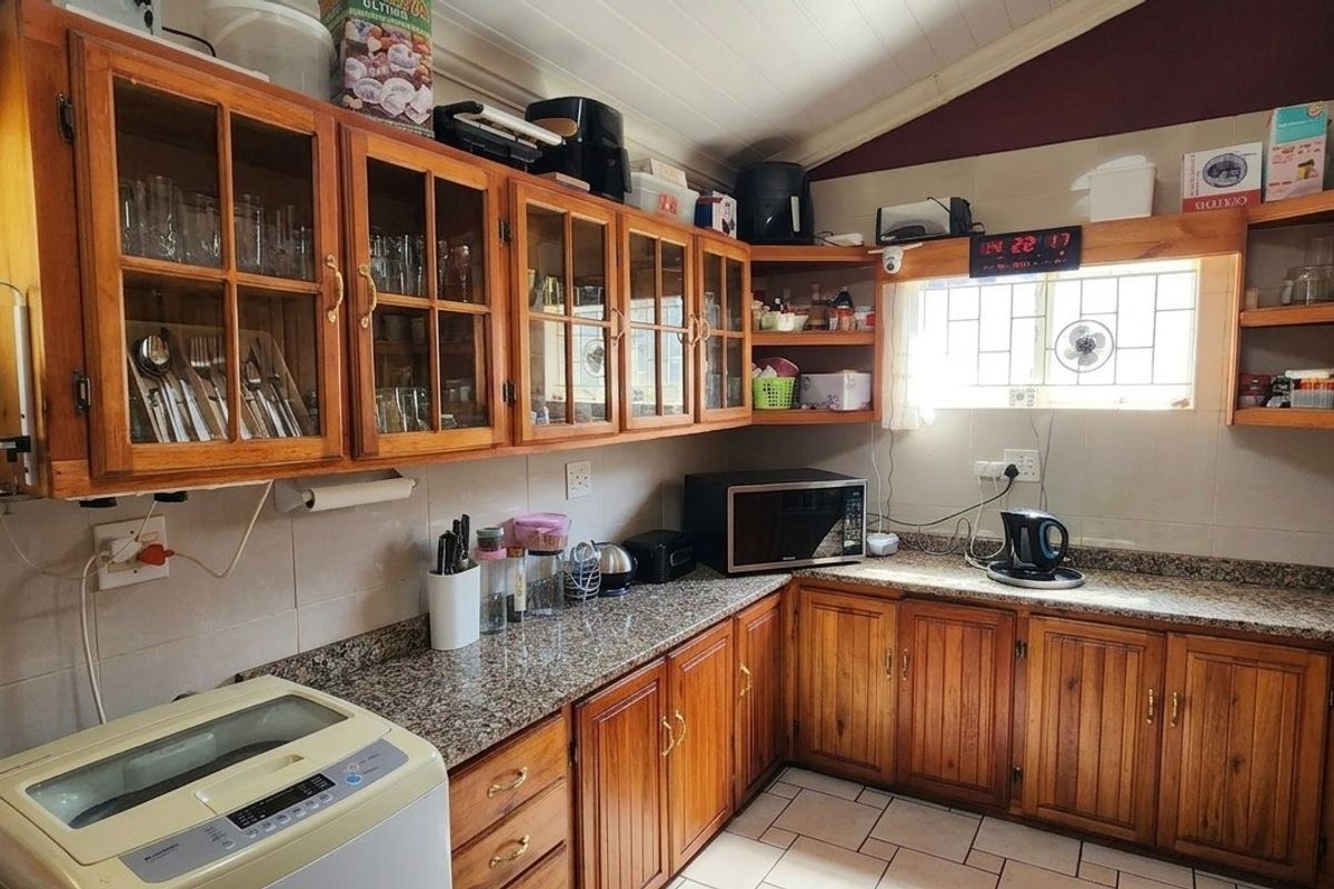 A functional kitchen featuring warm wooden cabinetry, granite countertops, and tiled flooring, offering a classic aesthetic with practical storage and workspace.