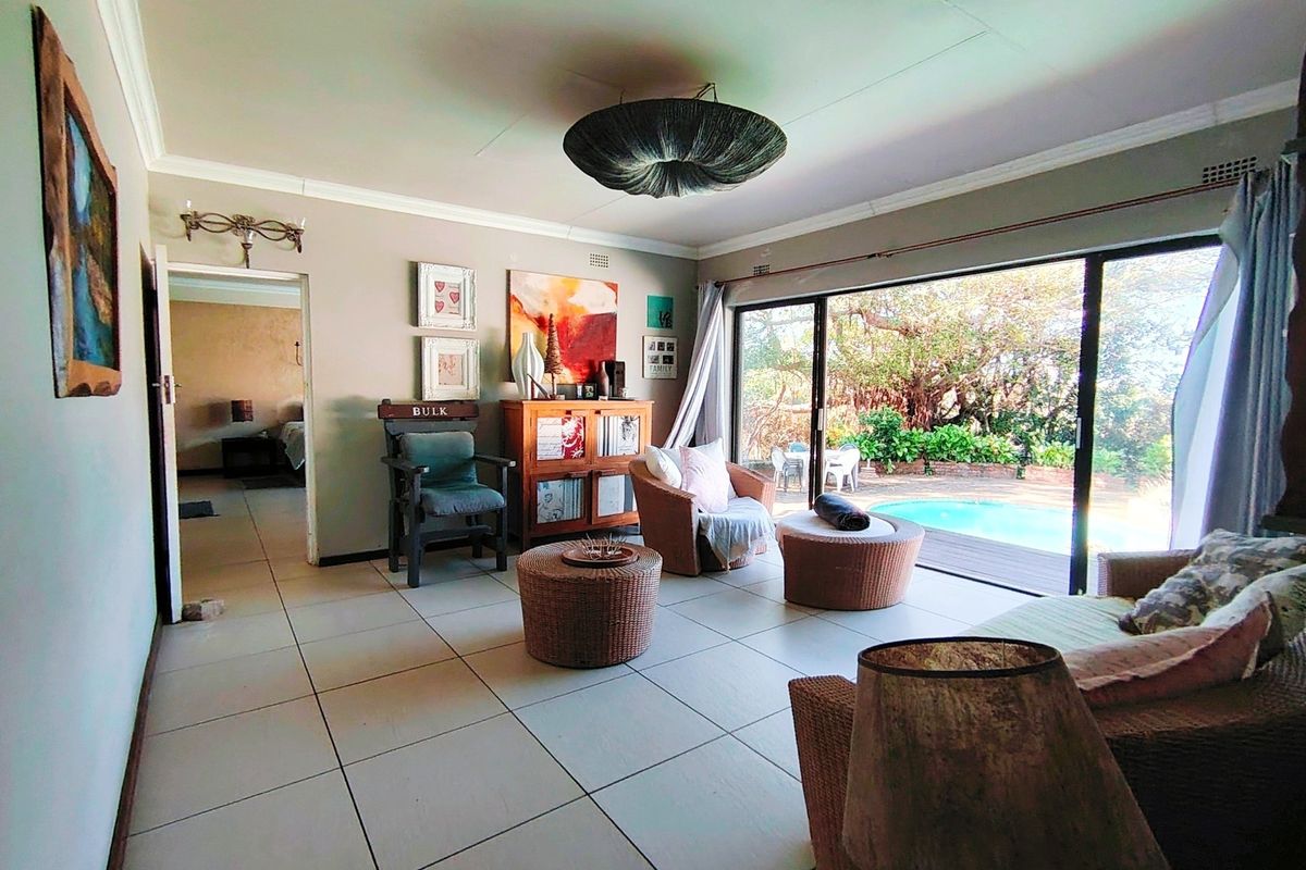 Spacious living room featuring large sliding glass doors that provide direct access to the outdoor pool area and garden.