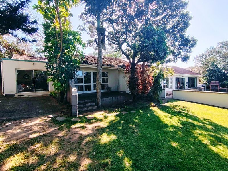 Rear view of the house featuring a tiled roof, sliding door access to a patio, and a built-in braai area overlooking the garden.