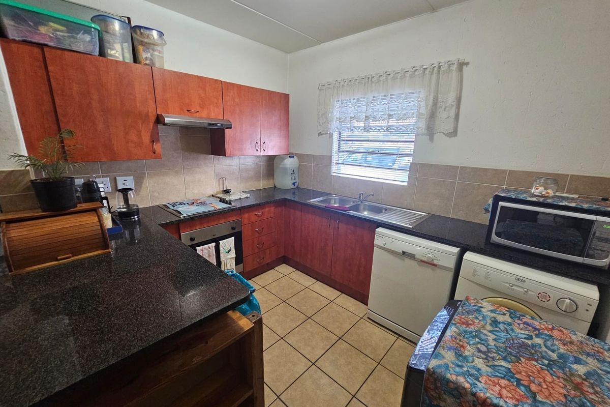 A functional kitchen featuring wood-finish cabinetry, granite countertops, tiled backsplash, and integrated appliances, offering a practical workspace for commercial or residential use.