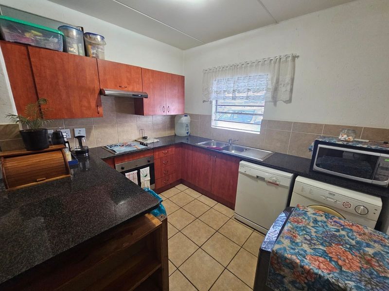 A functional kitchen featuring wood-finish cabinetry, granite countertops, tiled backsplash, and integrated appliances, offering a practical workspace for commercial or residential use.