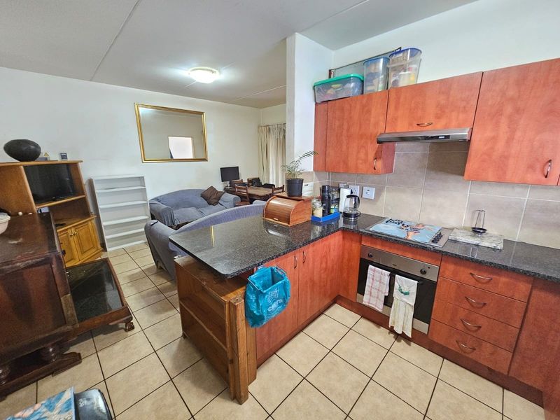 Open-plan living area featuring a functional kitchen with granite countertops, built-in oven, hob, and tiled flooring throughout the combined space.