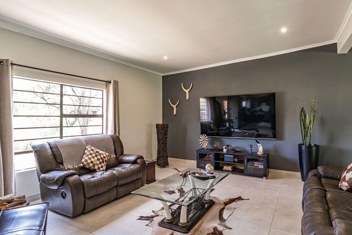 A well-maintained living room featuring neutral tiled flooring, a dark accent wall, and recessed lighting, creating a comfortable and modern atmosphere.