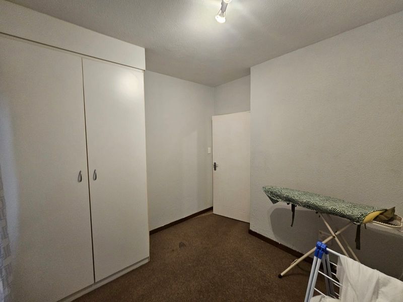 A simple bedroom featuring built-in wardrobes and carpeted flooring, offering a blank canvas for potential updates or restyling.