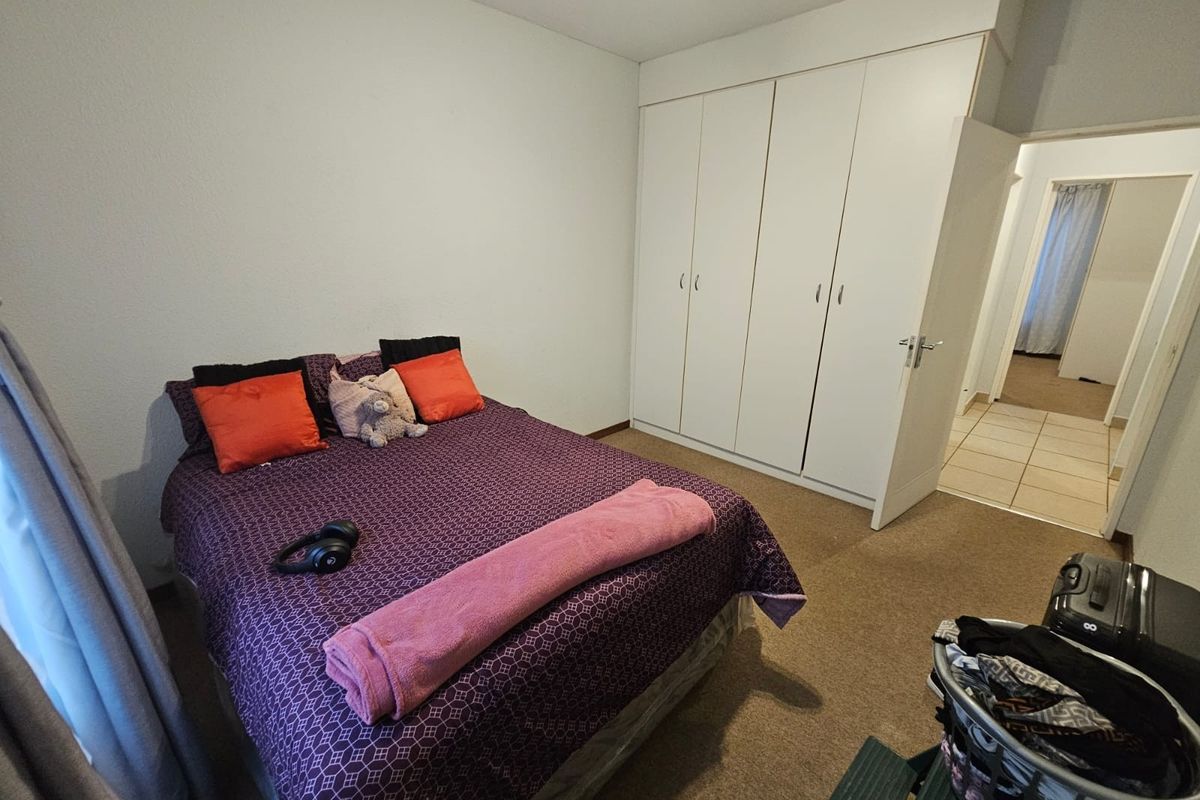 A functional bedroom featuring built-in cupboards and carpeted flooring, providing a comfortable and practical living space.