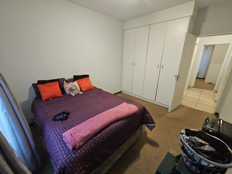 A functional bedroom featuring built-in cupboards and carpeted flooring, providing a comfortable and practical living space.