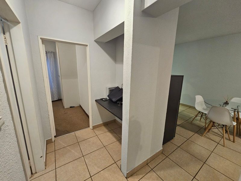 A functional hallway area featuring tiled flooring and a built-in desk nook, providing a transition space between rooms in this townhouse.