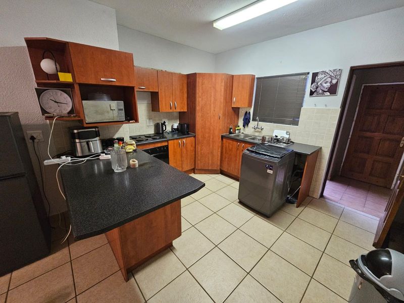 Functional kitchen featuring wood-look cabinetry, laminate countertops, built-in oven, hob, and tiled flooring with a practical layout.