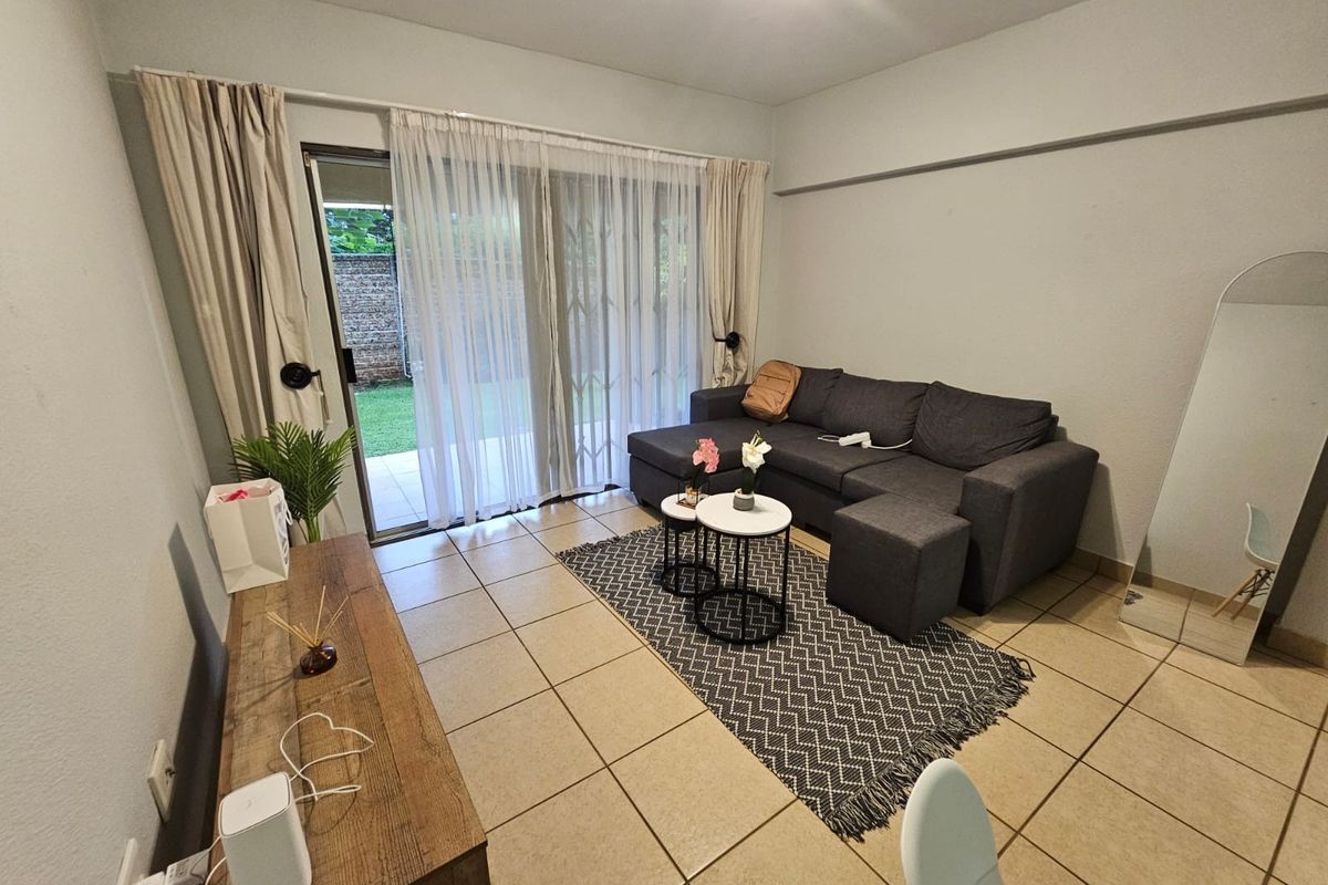 A living room featuring neutral tiled flooring and a sliding glass door that provides direct access to the outdoor patio area.