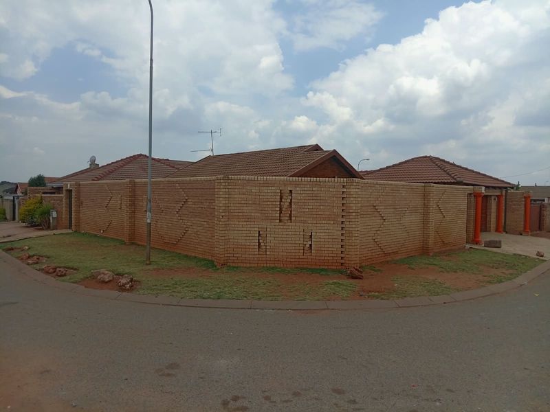 A street-facing view of a residential property featuring a face brick boundary wall and a tiled roof structure.