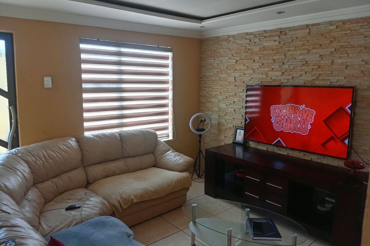 A comfortable living room featuring a textured stone cladding feature wall, recessed ceiling details, and neutral tiled flooring.