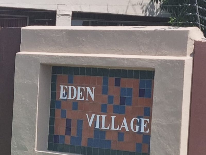 The entrance signage for Eden Village featuring a masonry wall with decorative tiling and integrated electric security fencing.