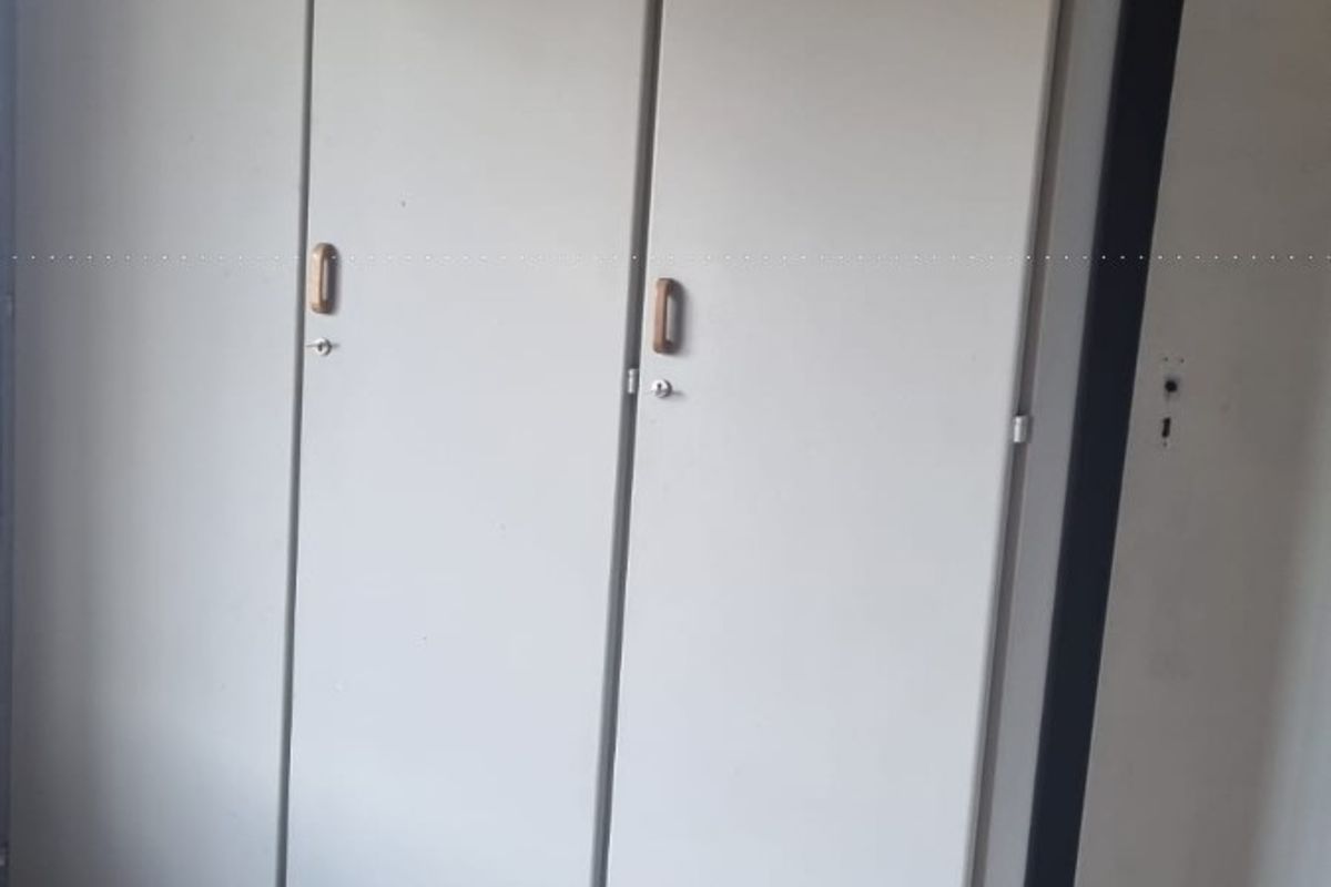 A bedroom featuring built-in cupboards and laminate flooring, offering a functional storage solution in a neutral space.