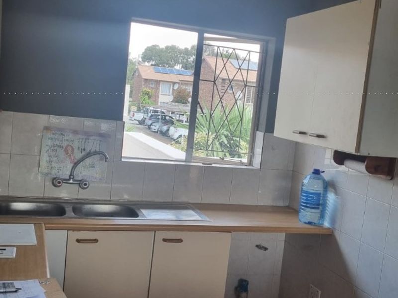 A functional kitchen featuring built-in cabinetry, a double sink, and tiled splashbacks, offering a practical layout with potential for modern updates.